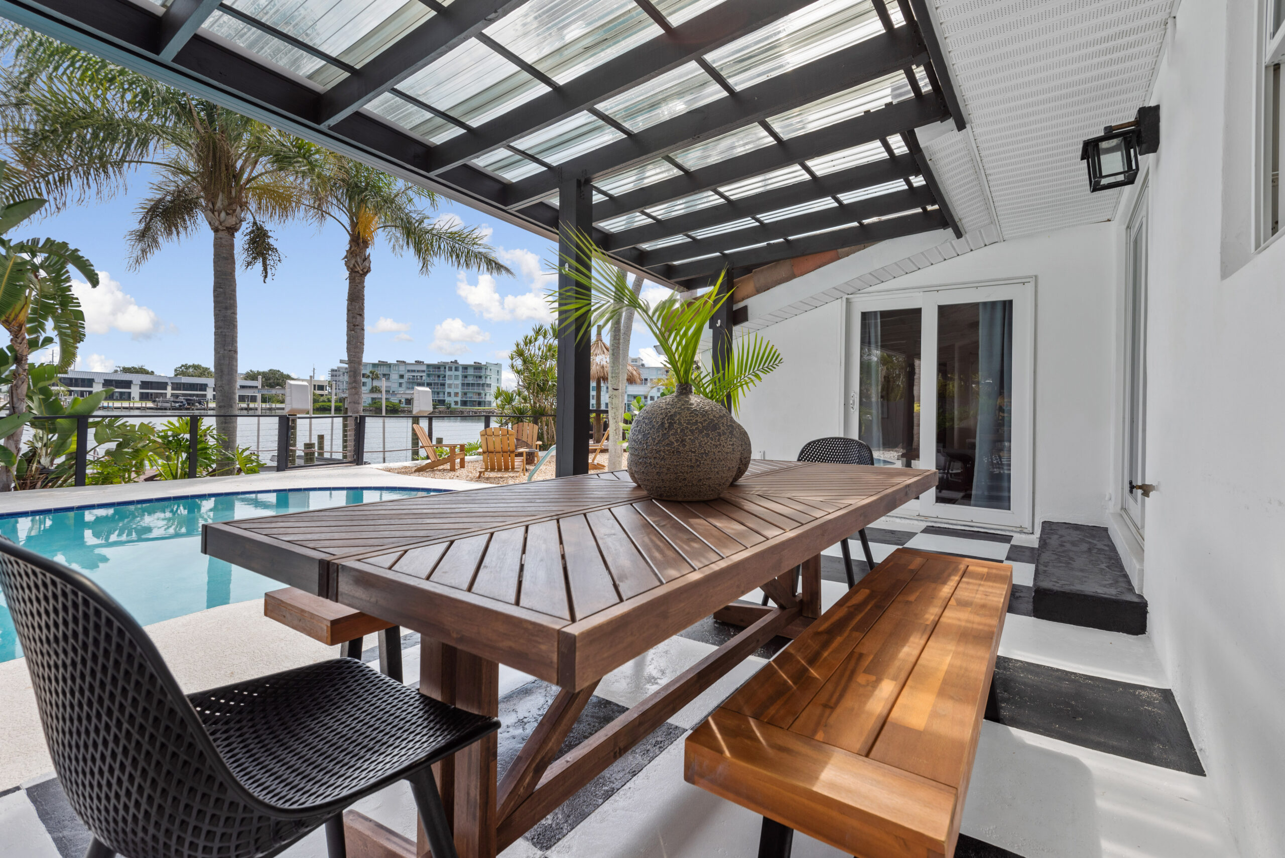 Outdoor dining area beside a private pool with tropical views at a boutique Cocoa Beach vacation home.