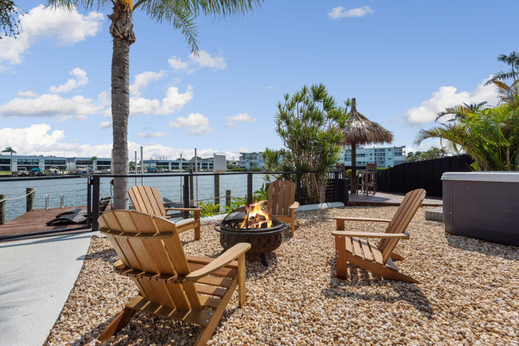 Outdoor waterfront seating area with wooden tables, palm trees, and calm water along Florida’s Space Coast