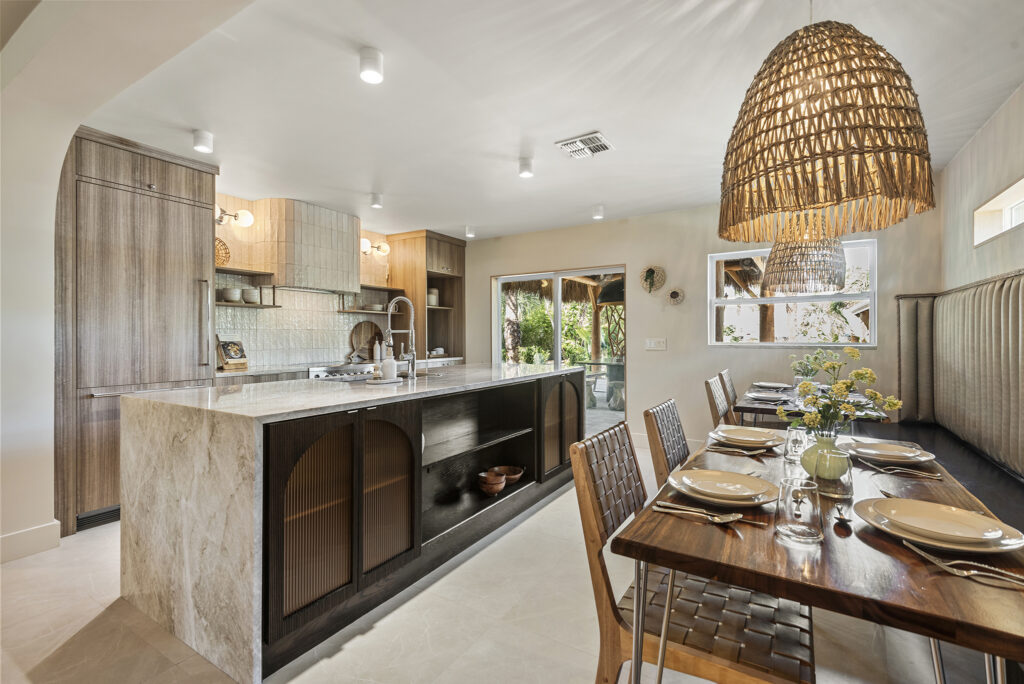 Modern open kitchen and dining area with natural wood accents, a large island, and a woven pendant light over the table.