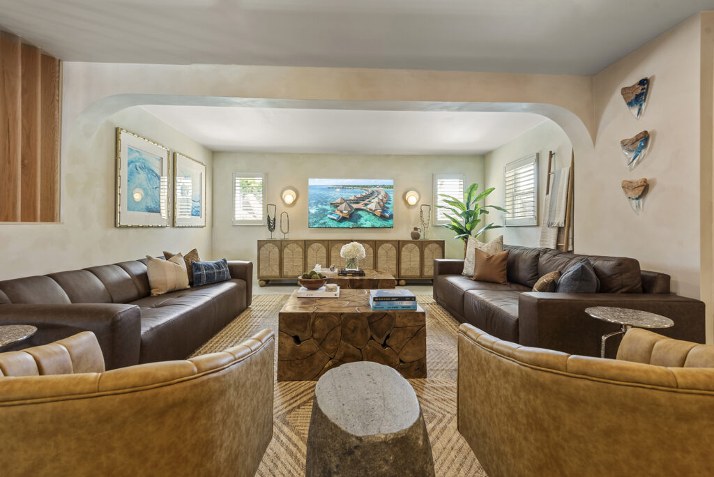 Stylish Cocoa Beach vacation rental living room with leather sofas, coastal artwork, and natural wood accents.