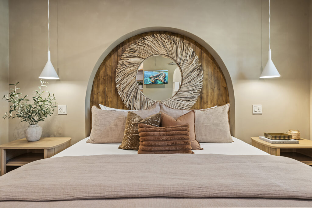 Stylish bedroom with neutral tones, decorative circular wall art above the bed, and modern pendant lights on each side.