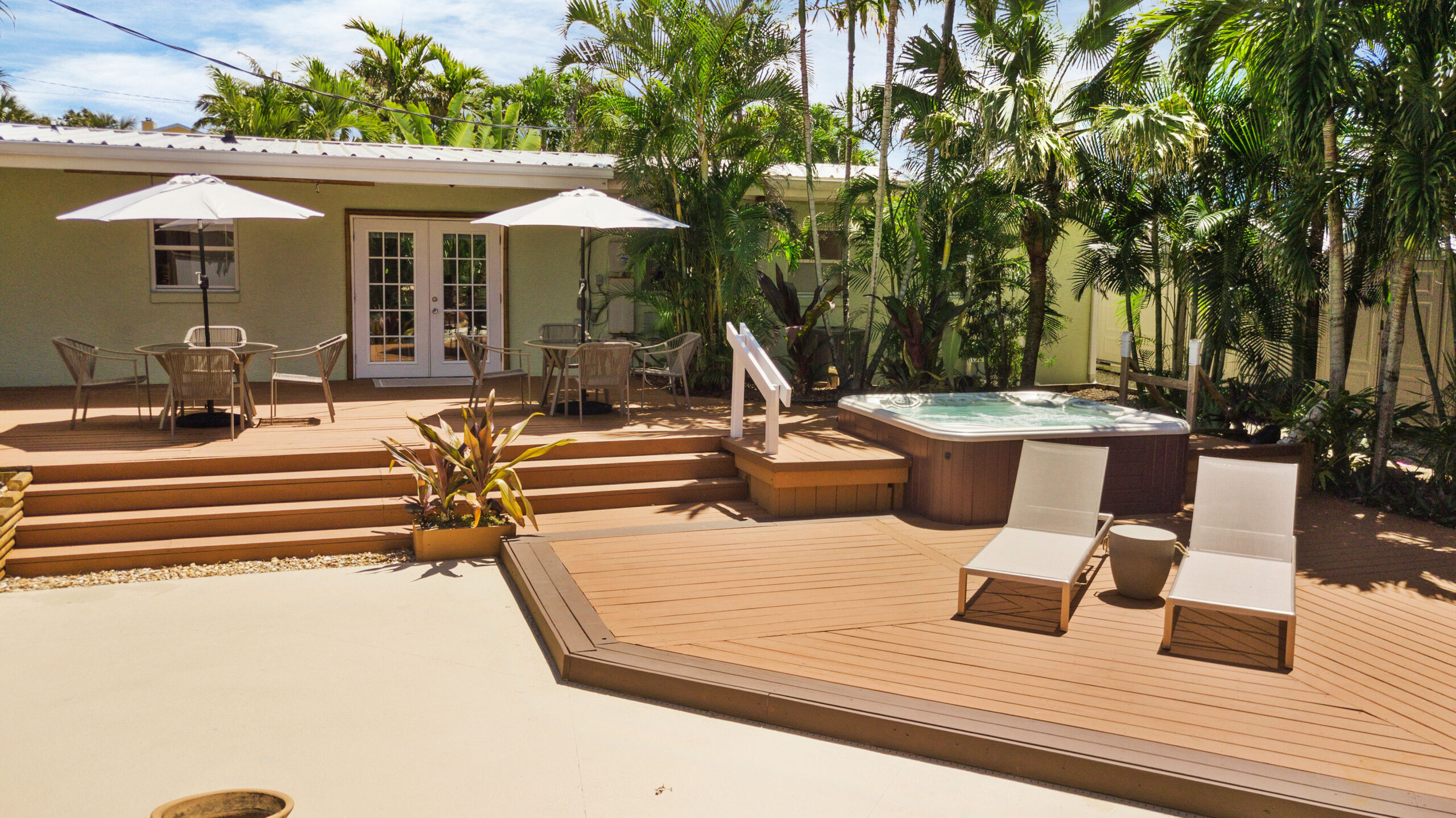 Outdoor patio with cushioned seating, pavers, and tropical greenery at a coastal vacation rental