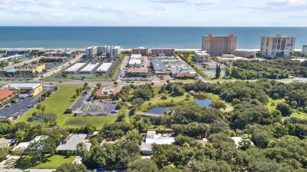Aerial view of Cocoa Beach neighborhood with the Atlantic shoreline and beachfront buildings on a sunny day.