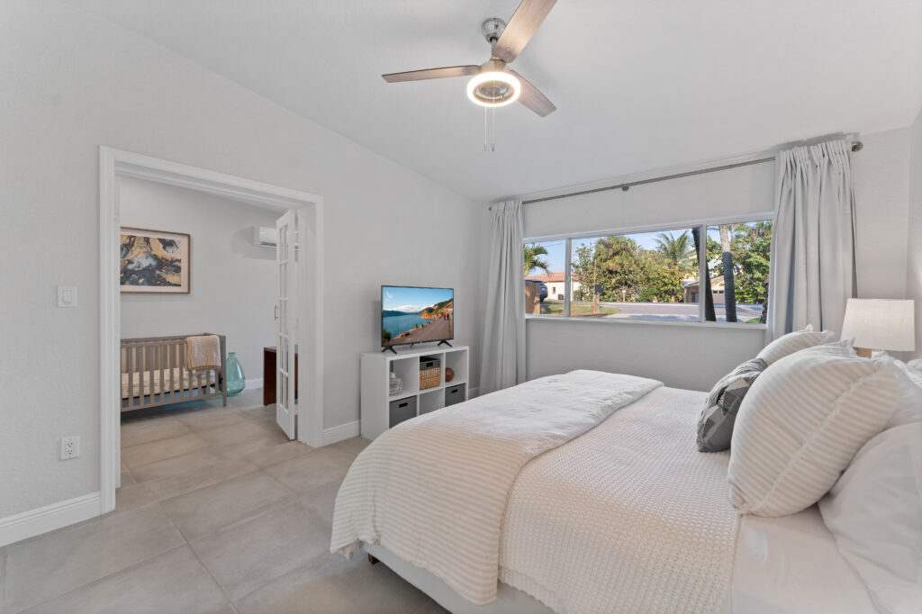 Bright coastal bedroom inside a boutique vacation home in Cocoa Beach with soft neutral decor and natural light.