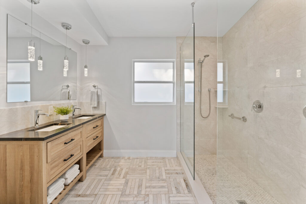 Modern bathroom with double vanity, glass walk-in shower, and natural wood accents at Footprint by Lalonde