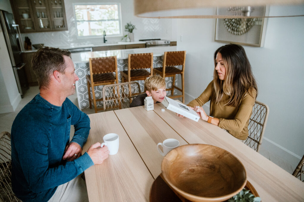 Family sitting together at a modern wooden dining table, sharing breakfast and enjoying a bright, airy kitchen.