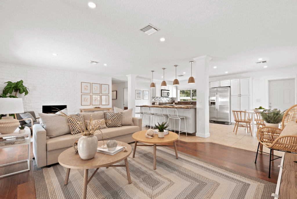 Open-concept living room and kitchen with neutral décor, woven accents, and modern pendant lighting.