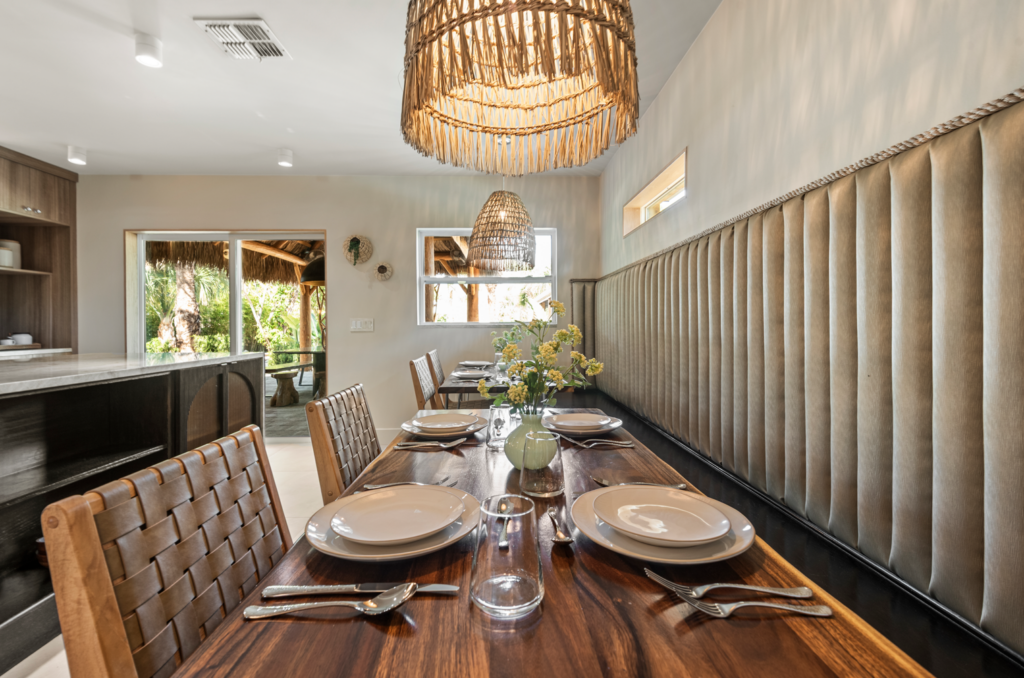 Dining table set for four beside a built in banquette in a bright open dining area.
